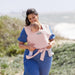 Moby Easy Wrap baby carrier rose shown worn by a woman holding a baby outdoors.
