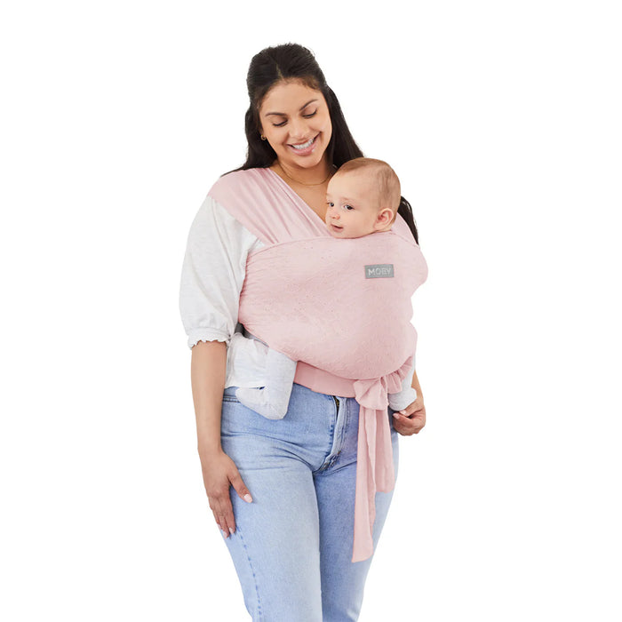 Moby Easy Wrap Baby Carrier Rose shown worn by a woman holding a smiling baby in front.