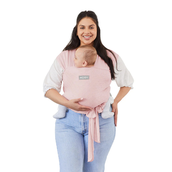 Moby Easy Wrap Baby Carrier Rose with baby in front, worn by smiling woman against white background.