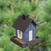 Blue cottage-style bird feeder hanging outdoors, filled with birdseed
