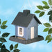 Blue cottage-shaped bird feeder with white door, hanging outdoors, leafy branches nearby