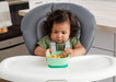 NUK suction bowl in teal held by a baby sitting in a high chair at a kitchen table.