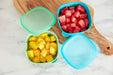 NUK suction bowls 2-pack in teal shown on a kitchen counter, filled with cubed fruit.