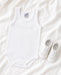 Petit Abeille baptism undershirt and white baby shoes displayed on soft white fabric.