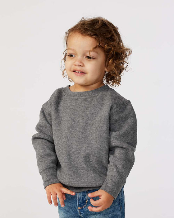 Toddler in grey fleece crew neck sweatshirt and blue jeans, plain background