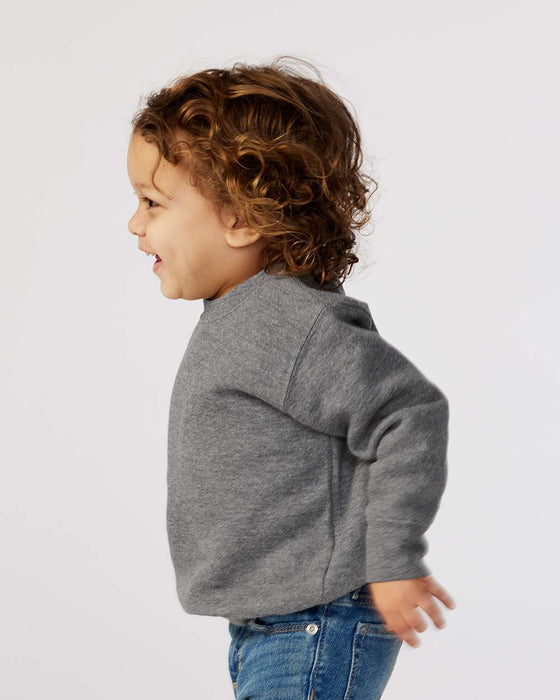 Smiling toddler in a grey fleece crew neck sweatshirt and blue jeans, side profile
