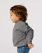 Smiling toddler in a grey fleece crew neck sweatshirt and blue jeans, side profile