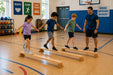 solid maple wooden balance board for kids - children in a school gym on the boards with the teacher supporting them