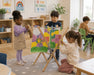 Solid Maple Wood Arts and Crafts Drying Rack for Kids with children hanging paintings in a daycare classroom