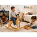 Solid durable maple wood classic rocking horse toy lifestyle in a kid bedroom with a boy on the horse and other children playing around - Goldtex