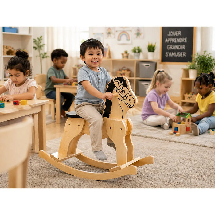 Solid durable maple wood classic rocking horse toy lifestyle image in a daycare with little boy on the horse and children playing around - Goldtex