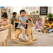 Solid durable maple wood classic rocking horse toy lifestyle image in a daycare with little boy on the horse and children playing around - Goldtex