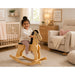 Solid durable maple wood classic rocking horse toy in a nursery or toddler room with a little girl proudly sitting on the horse - Godltex