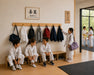 Solid wooden wall mount coat rack with 7 hooks in a martial arts dojo with children hanging their coats and bags