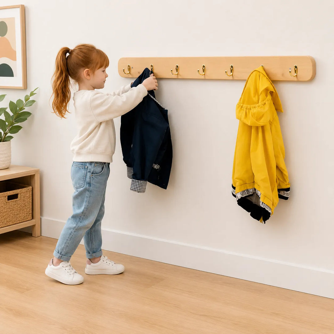 Child hanging her jacket on a solid wooden coat rack