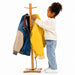 Child hanging a yellow jacket on the hard wood coat rack with other jackets.