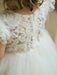 Warm Wendy off white lace baptism dress shown from the back on a young child indoors.