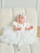 Warm Wendy Off-White Lace Baptism Dress shown on a baby sitting on a cream textured chair.