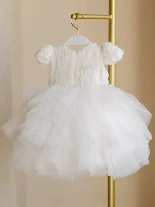 Warm Wendy off-white lace baptism dress with tulle skirt, displayed on a hanger indoors.