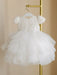 Warm Wendy off-white lace baptism dress with tulle skirt, displayed on a hanger indoors.
