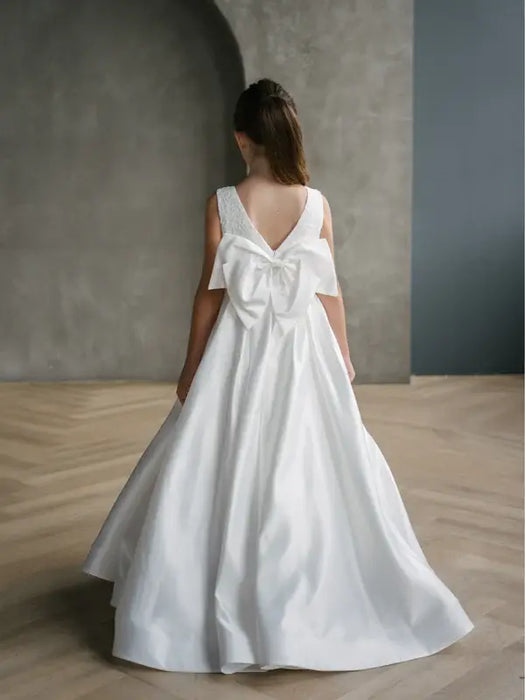 Teter Warm Tara satin bow communion dress shown on a girl standing indoors facing away