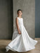 Teter Warm Tara satin bow communion dress shown on a young girl standing indoors against a gray wall.