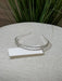 Teter Warm Ace double band headpiece with crystals displayed on a textured table in front of green plants.