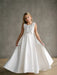 Addison satin bow shoulder communion dress on a young girl standing indoors against a gray backdrop.