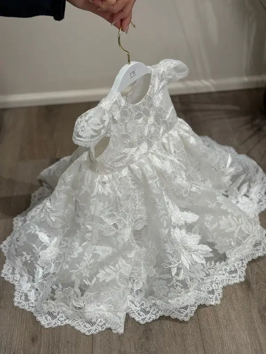 Teter Warm Adele off-white floral lace baptism dress on hanger, displayed indoors on wood floor.