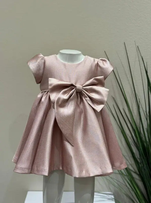 Teter Warm Ailani pink metallic party dress with large bow displayed on a child mannequin indoors.