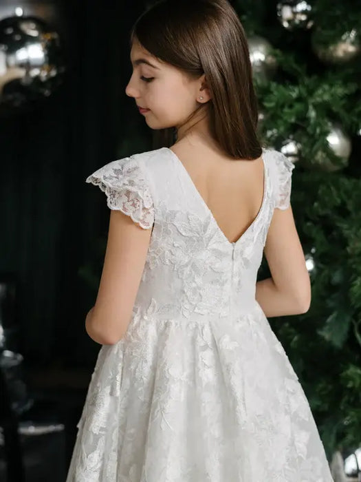 Teter Warm Angelica Lace Communion Dress shown on a girl standing near a decorated tree.