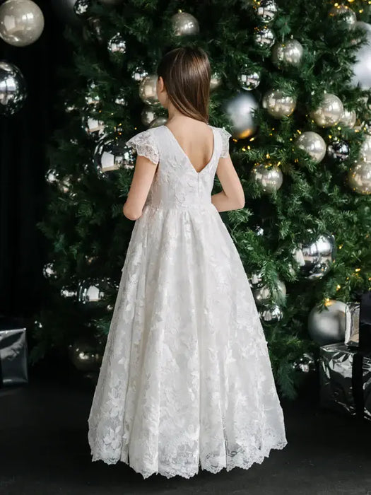 Angelica Lace Communion Dress shown on a girl standing in front of a decorated Christmas tree.