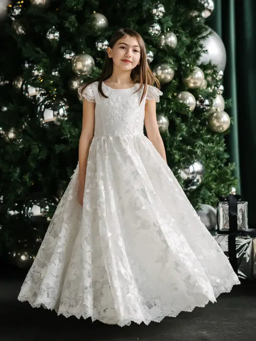 Angelica Lace Communion Dress shown on a girl standing in front of a decorated Christmas tree.