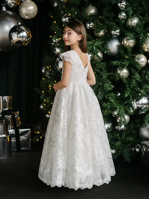 Teter Warm Angelica Lace Communion Dress shown on a girl standing by a decorated Christmas tree.