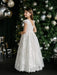 Teter Warm Angelica Lace Communion Dress shown on a girl standing by a decorated Christmas tree.