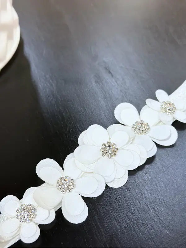 Teter Warm baby girl floral headband with rhinestones displayed on a dark wooden surface.