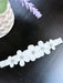 Warm baby girl floral headband with rhinestones on a dark tabletop, featuring white flowers.