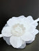 Teter Warm baby girl white headband with large layered fabric flower displayed on a dark surface.
