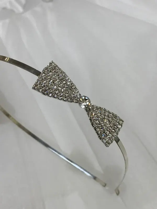 Teter Warm Beatrix Silver Headband with a sparkly bow detail displayed on white fabric.