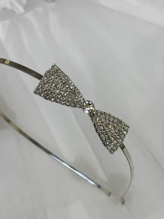 Teter Warm Beatrix Silver Headband with a sparkly bow detail displayed on white fabric.