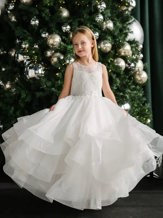 Teter Warm Billie off-white communion dress worn by a girl posing in front of a decorated Christmas tree.