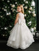 Teter Warm Billie off-white communion dress with bow, worn by a girl standing by a decorated tree.
