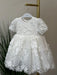 Teter Warm Carlita 3D floral lace baptism dress hanging on a white hanger against a neutral background.