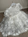 Teter Warm Carlita 3D floral lace baptism dress displayed on a hanger against a wooden floor.