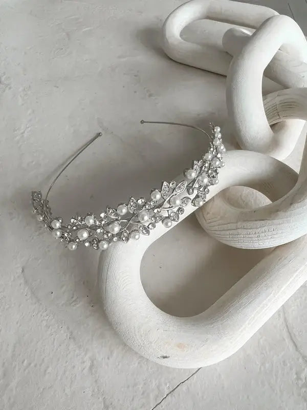 Cecilia Rhinestone Headpiece with pearls and crystals displayed on a white sculptural surface.