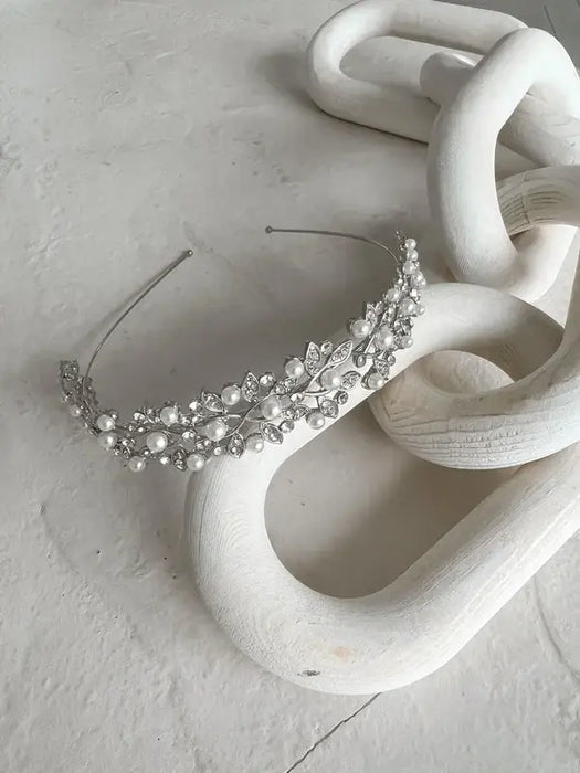 Cecilia Rhinestone Headpiece with pearls and crystals displayed on a white sculptural surface.