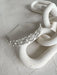 Cecilia Rhinestone Headpiece with pearls and crystals displayed on a white sculptural surface.