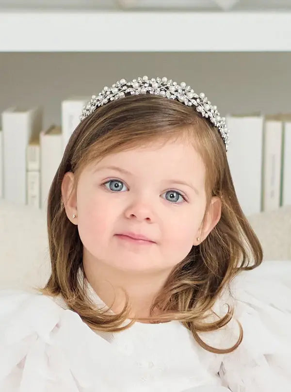 Cecilia Rhinestone Headpiece worn by a young girl in a white dress, seated indoors