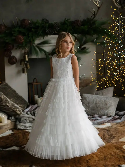 Teter Warm Celeste off-white communion dress worn by a girl standing indoors with festive decor.