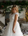 Teter Warm Celeste off white communion dress worn by a girl standing indoors near festive decor.